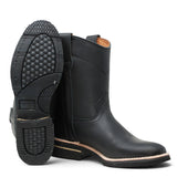 Bota de trabajo para hombre de piel graso color Negro con suela de hule, usada en ambiente de taller con jeans y guantes de trabajo. 