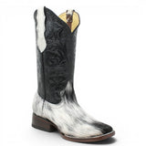 Bota vaquera para dama de pelo de vaca natural en tonos blanco y negro con punta cuadrada, tubo negro de piel con grabado cincelado floral y suela de cuero artesanal. Cada par presenta un patrón de pelo único. 1 angle
